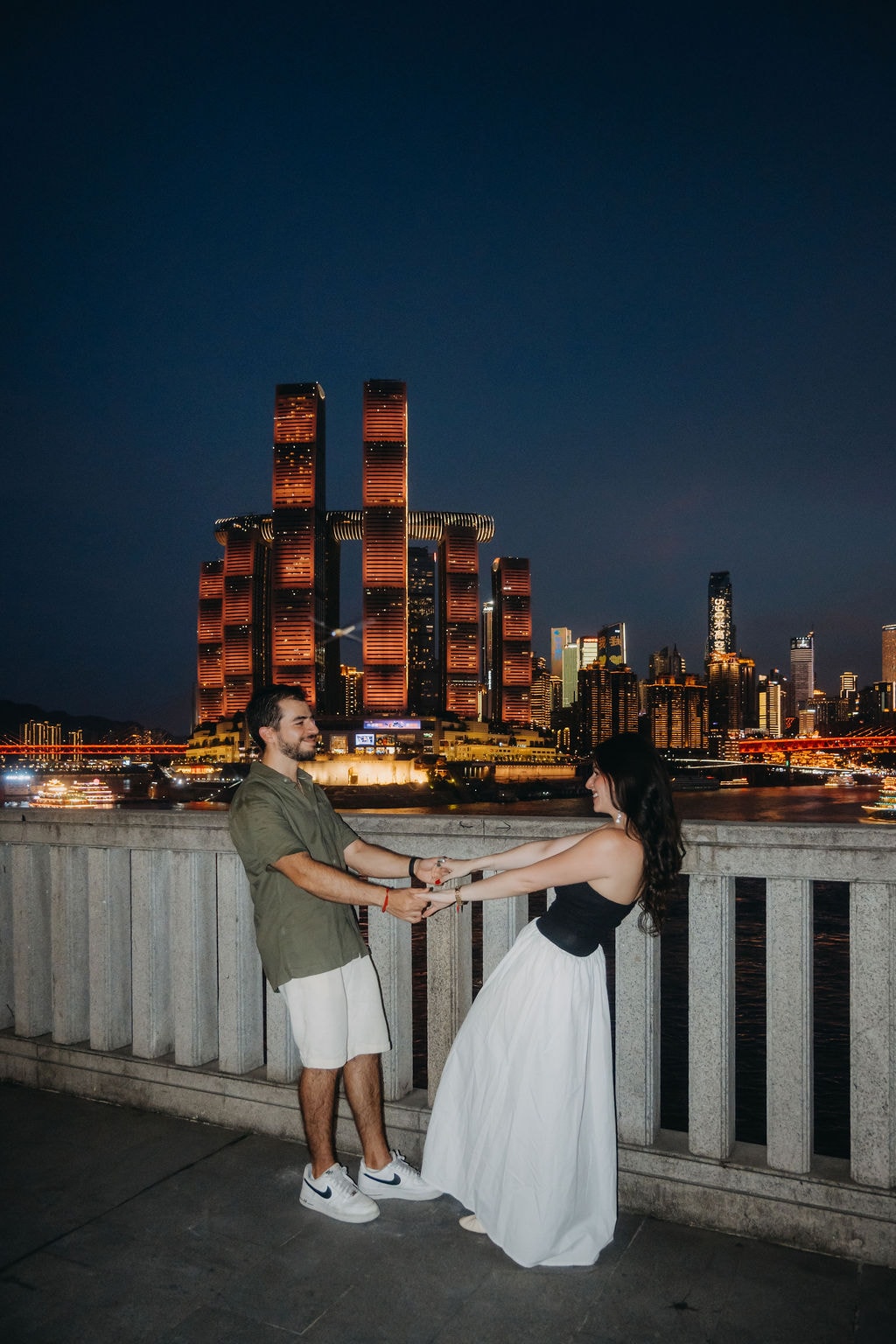 Couple portrait by the river at night in Chongqing, with Raffles City skyline as the background.